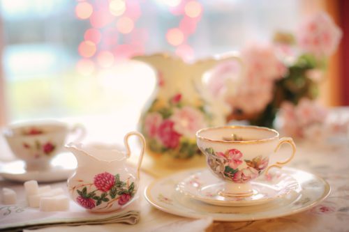 Vintage floral tea set with delicate pink rose patterns, evoking the charm of traditional English afternoon tea served with milk & sugar in "A History On Tea". The Brits generally prefer their tea black, in tea-bags with milk and often with sugar.