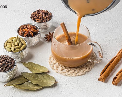 Spiced Indian chai being poured with whole spices beside it, illustrating regional tea styles featured in A History On Tea. Indians prefer their tea black, loose-leaf, usually serving a spiced 'masala chai' with milk, sugar and spices such as cardamon, cinnamon, black pepper, nutmeg, cloves or ginger.