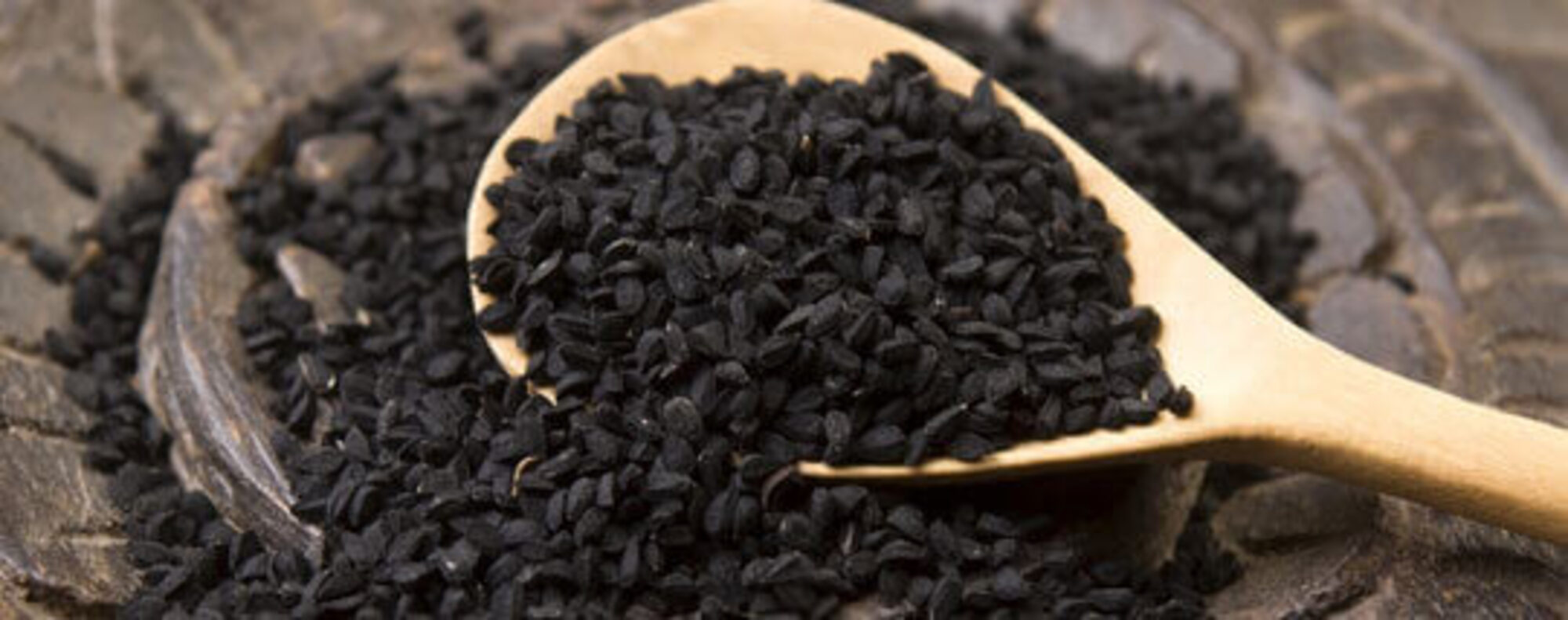 close up of black seeds on a wooden spoon