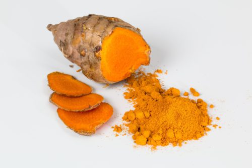 Fresh turmeric root and bright orange turmeric powder side by side, a vivid visual cue to the main ingredient of Turmeric Golden Milk.