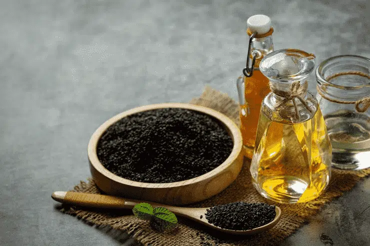 Natural black seed oil and seeds displayed on a rustic table, one of the top natural sleep remedies for calming the nervous system.