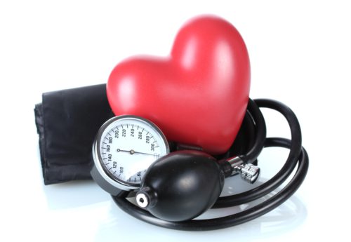 Blood pressure monitor and red heart shape symbolizing heart health benefits often linked to what is in green tea.