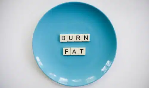 the letters on scabble tiles spell 'burn fat' on a blue plate