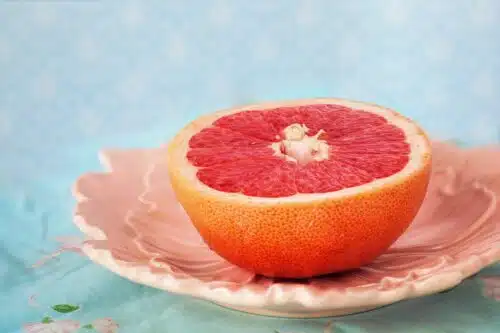 Half a grapefruit on a decorative plate, a popular citrus among belly-fat burning foods for its metabolism-boosting properties.