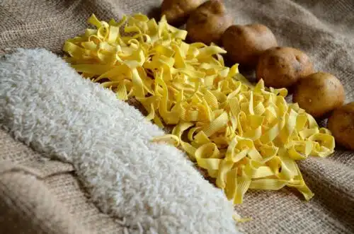Raw rice, pasta, and potatoes on a burlap cloth, highlighting one of the most common weight loss myths: that carbs are always the enemy.
