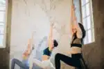 a group of three woman doing the same yoga pose in a well lit studio