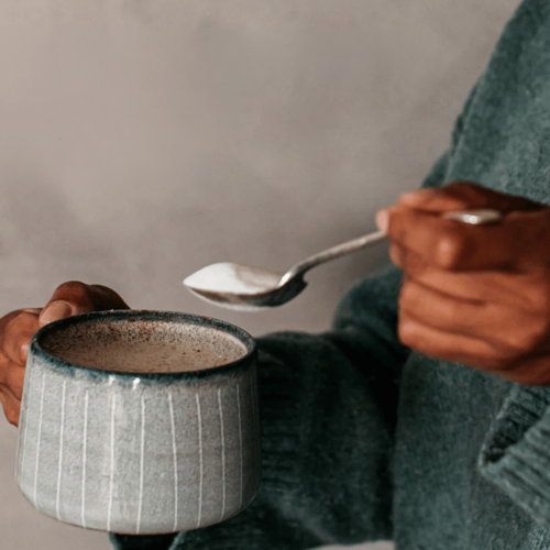 Hand stirring marine collagen into a warm drink, showing an easy daily wellness ritual for glowing skin and joint support.