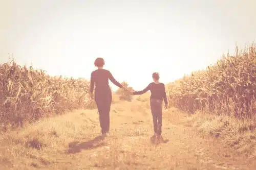 Mother and child holding hands on a sunlit path through a cornfield, symbolizing generational patterns and the question—is your partner echoing your parent?