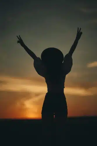 Silhouette of a woman raising peace signs at sunset, representing healing and self-awareness—after asking, is your partner echoing your parent?