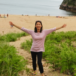 Profile – Blending Herbal Tea Image of Blending Herbal Tea owner on a beach with outstretched arms